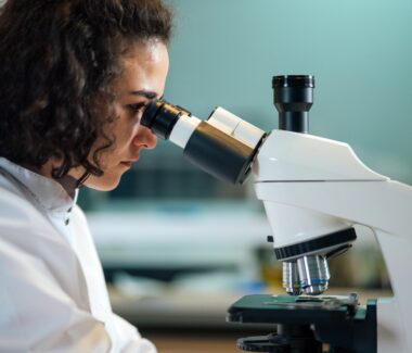 Female scientist looking through a microscope at a blood sample
