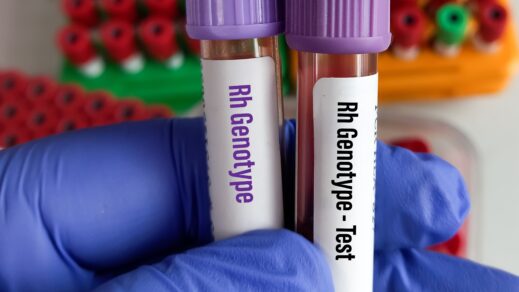 Gloved hand of lab technician holding vial of blood